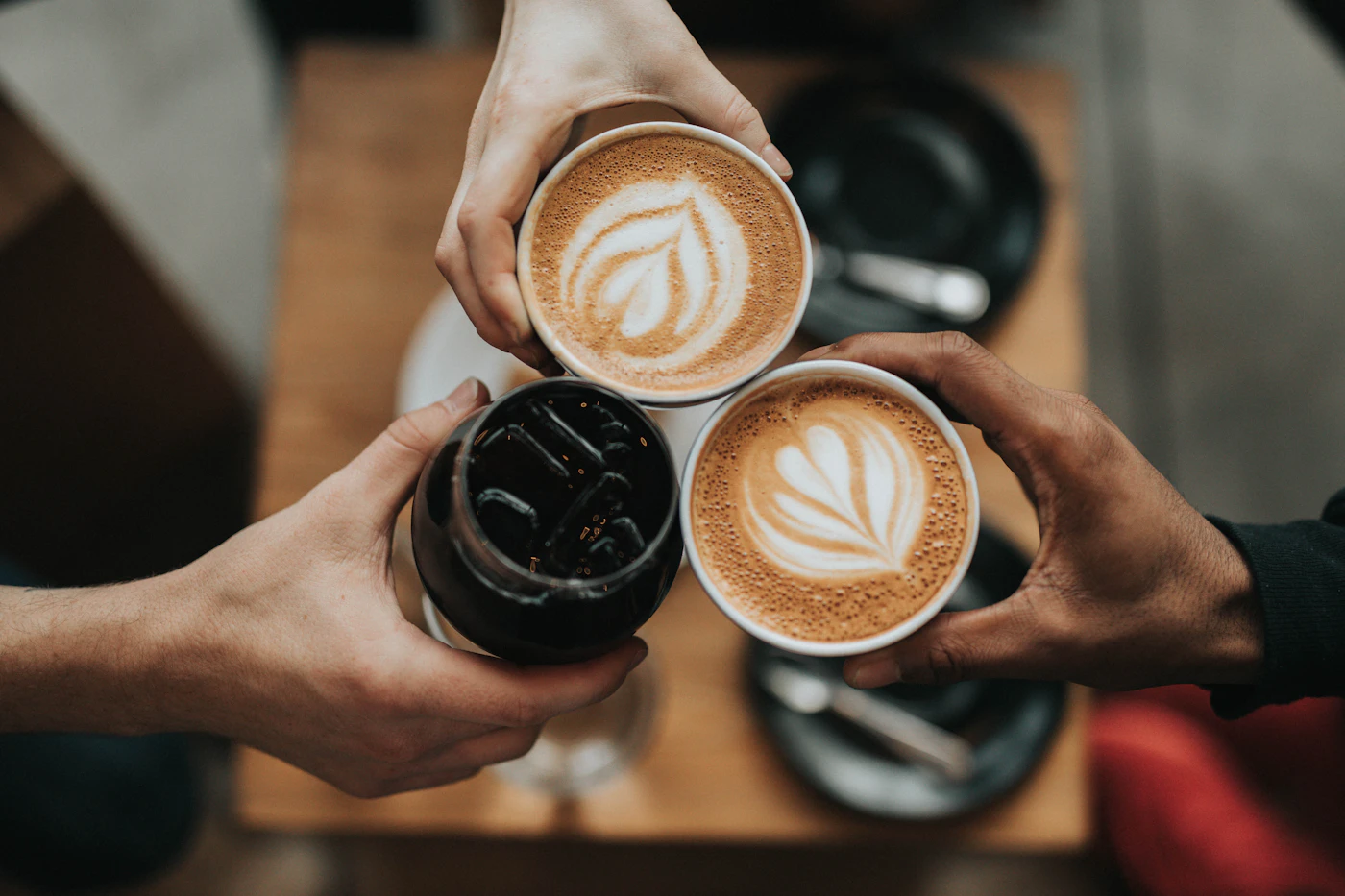 Overhead photo of a cup of coffee on a wooden café table in morning light